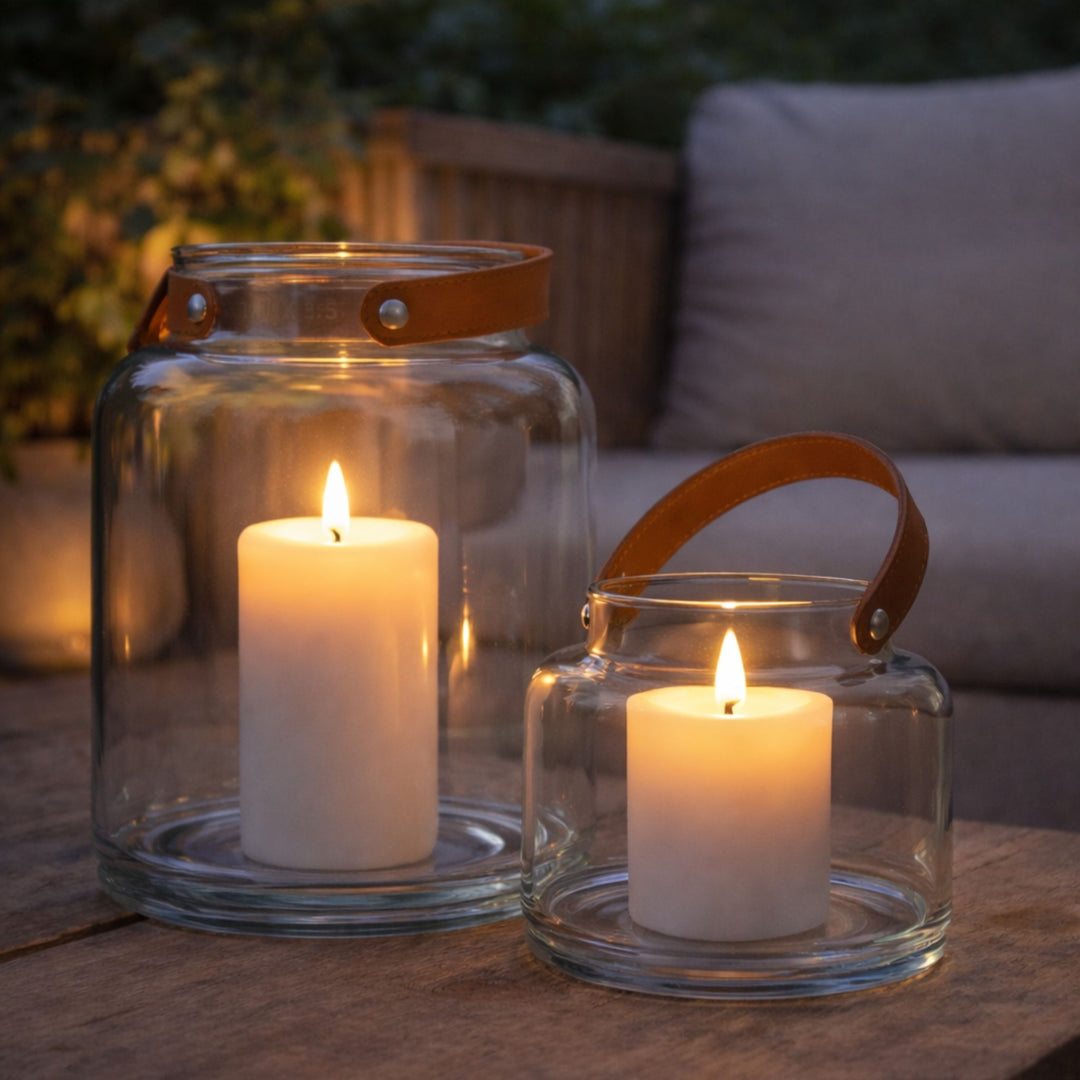 Small and large hand-blown glass candle lanterns with white faux pillar candles styled outdoors for a cosy summer evening setting